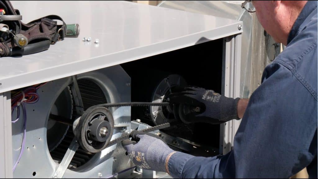 HVAC technician repairing a non-working AC fan motor, addressing common causes like capacitor failure and wiring issues.