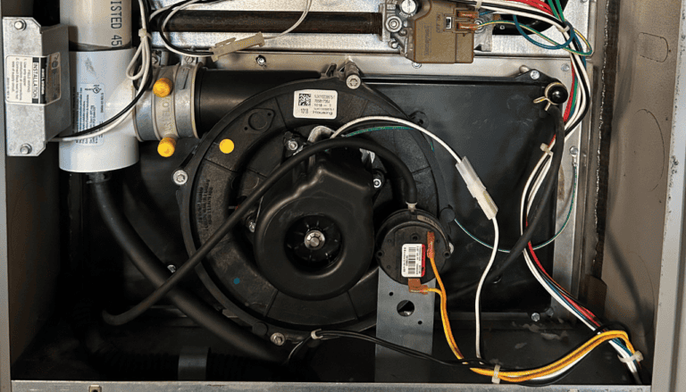 lose-up of a furnace inducer motor with visible wiring and components, showcasing electrical connections and mechanical assembly for troubleshooting.